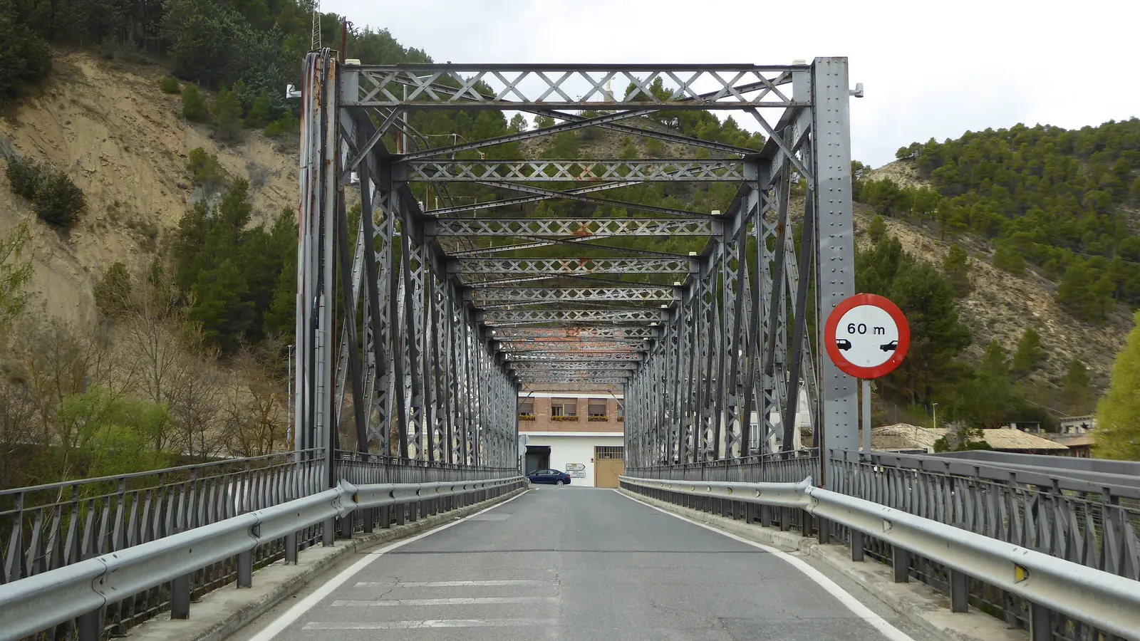 Calzada del Puente de Hierro de Sangüesa, con su celosía de acero y al fondo una señal de dirección